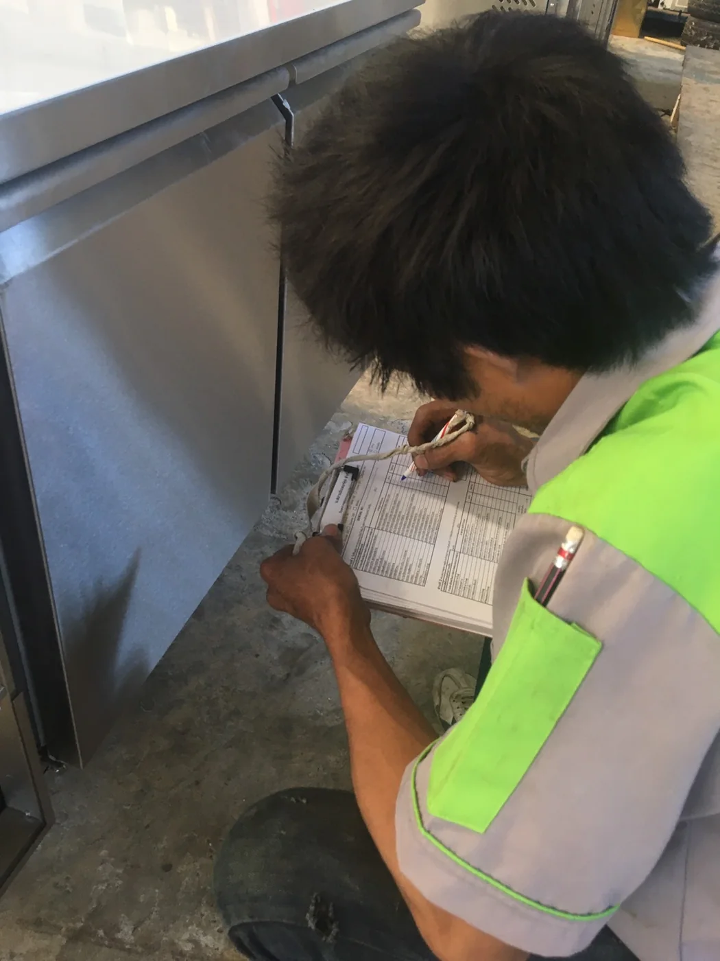 Technician completing a commercial refrigeration quality-control checklist